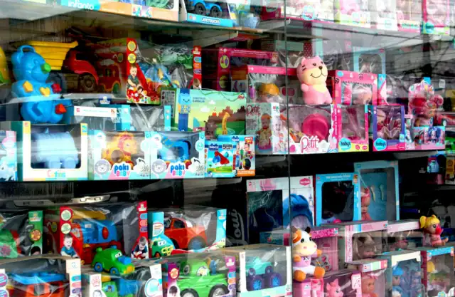 Игрушки в коробках и мягкие игрушки на полках за витриной